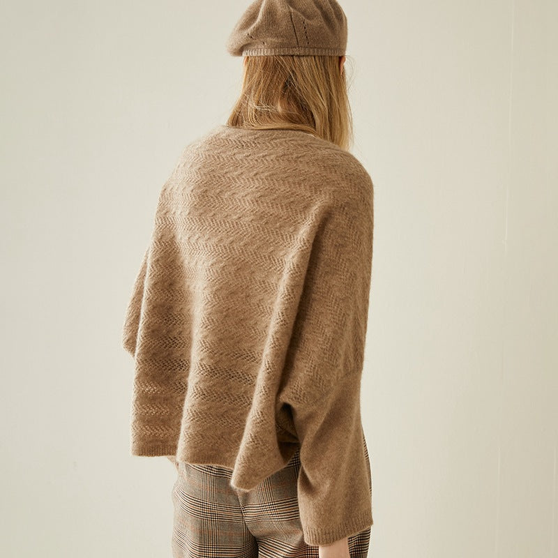 Person wearing a brown knitted sweater and hat against a plain background