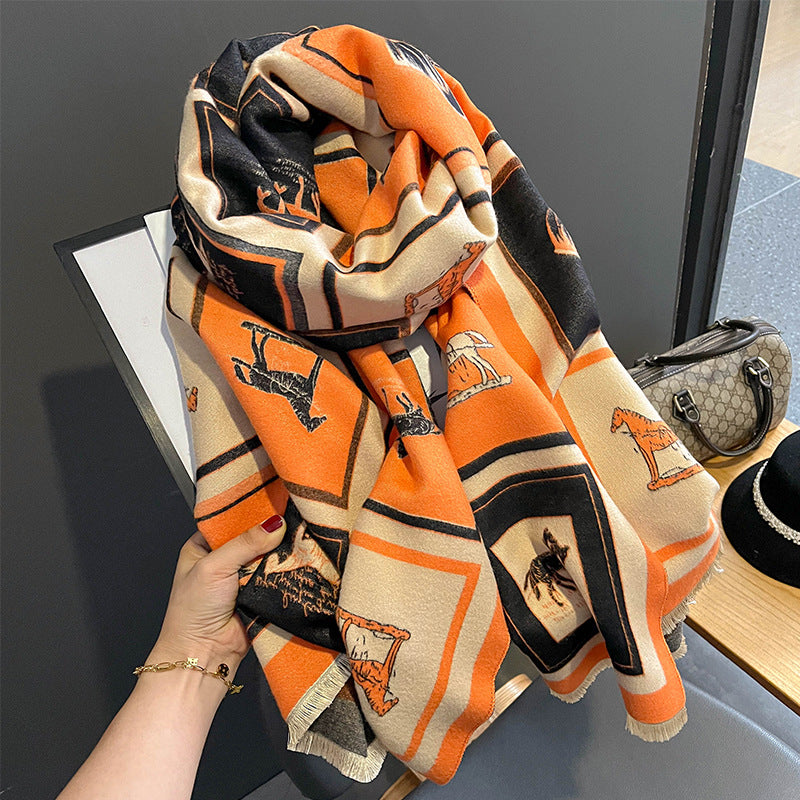 Orange and beige patterned scarf held by a hand with horses