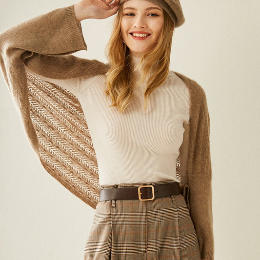 Woman wearing a brown sweater, white shirt, plaid skirt, and hat on a plain background