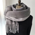 Gray scarf with fringes draped over a black garment on a white background