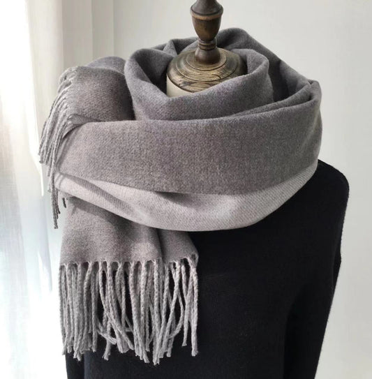 Gray scarf with fringes draped over a black garment on a white background