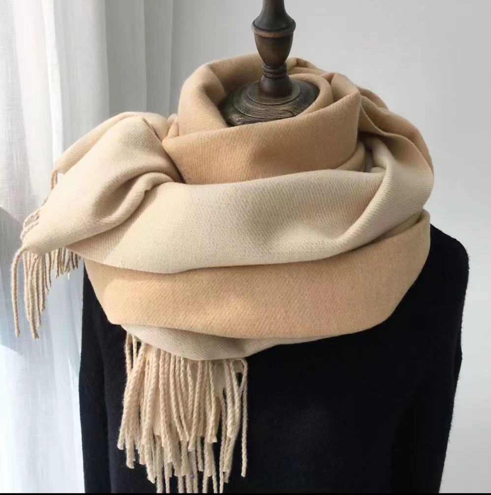 Beige scarf with fringes draped over a mannequin against a white background