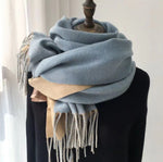 Light blue scarf with beige accents draped over a mannequin against a neutral background