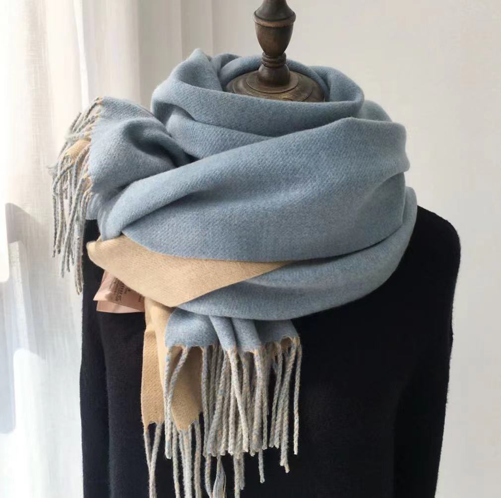 Light blue scarf with beige accents draped over a mannequin against a neutral background